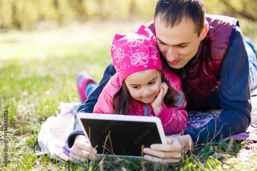 Young father and little cute daughter reading in summer park Young father and little cute daughter reading in summer park