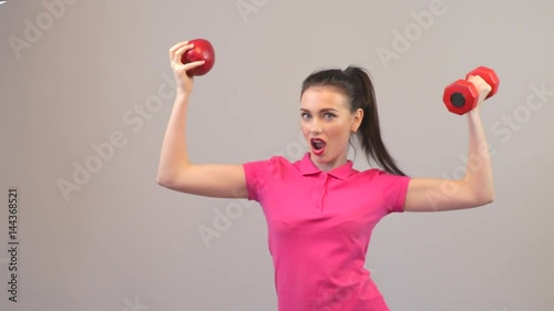 Elements of a healthy lifestyle. Attractive young woman possing with apple and dumbbell