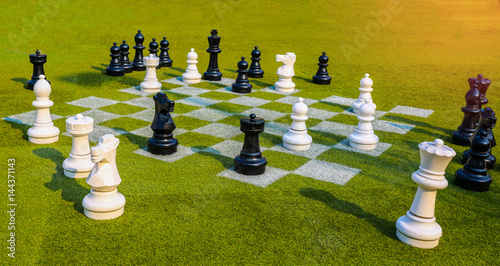 Chessboard and chess pieces on the grass in the garden,playing wooden chess pieces, business teamwork competition games concept, leadership hand of businessman