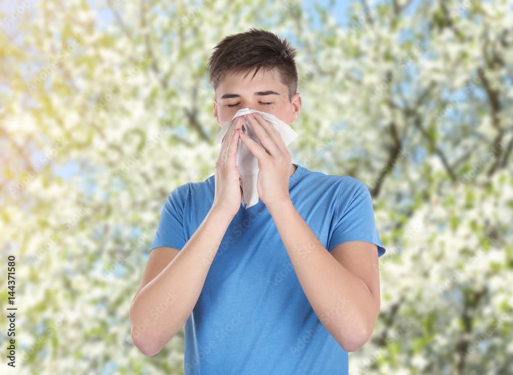 Young man blowing nose on tissue against white background Young man blowing nose on tissue against white background