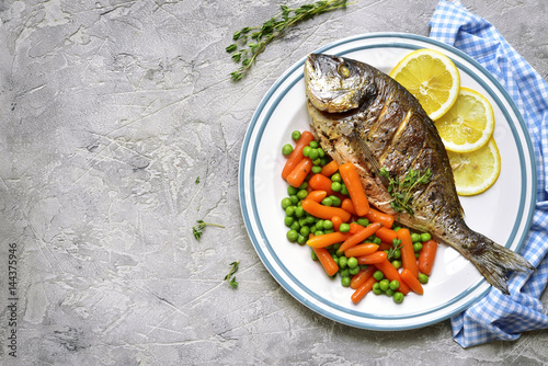 Baked dorado or sea bream with spring vegetables.Top view with copy space.
