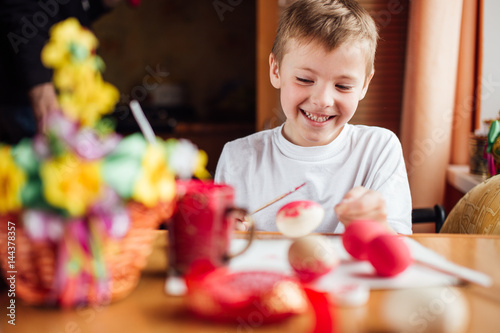 Young boy drawing easter eggs at home and smile