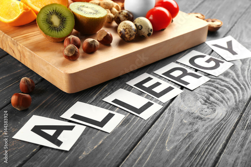 Word ALLERGY and food on wooden background