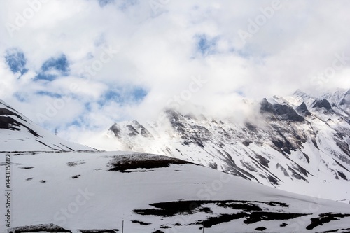 Горный пейзаж, красивый вид на высокие снежные склоны, небо в белых облаках. Горы и природа Северного Кавказа, Грузия