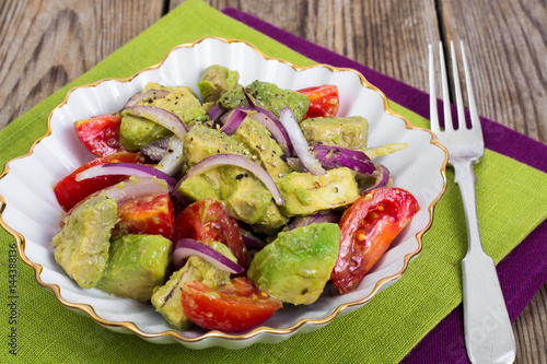 Salad with avocado and tomatoes on wooden background