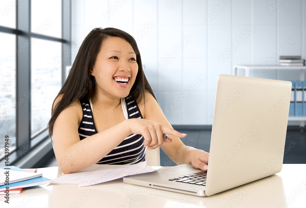 happy chinese asian woman working and studying on her computer sitting at modern office desk smiling cheerful happy chinese asian woman working and studying on her computer sitting at modern office desk smiling cheerful