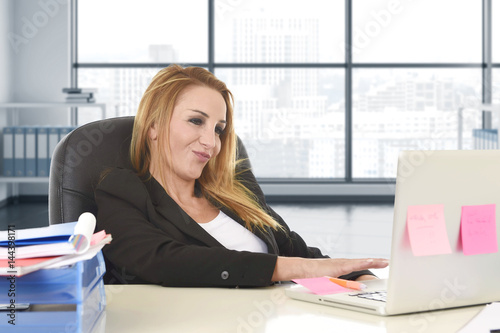 relaxed 40s woman with blond hair smiling confident sitting on office chair working at laptop computer