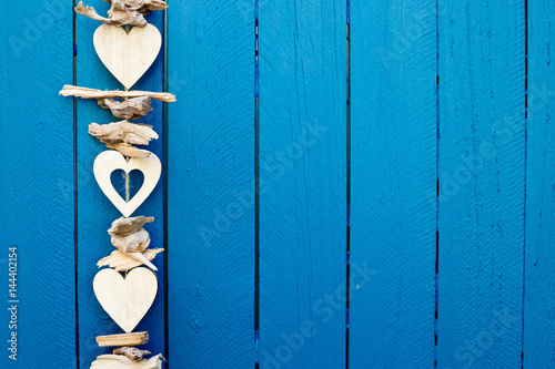 Background - Decorative drift wood hearts hanging on blue fence
