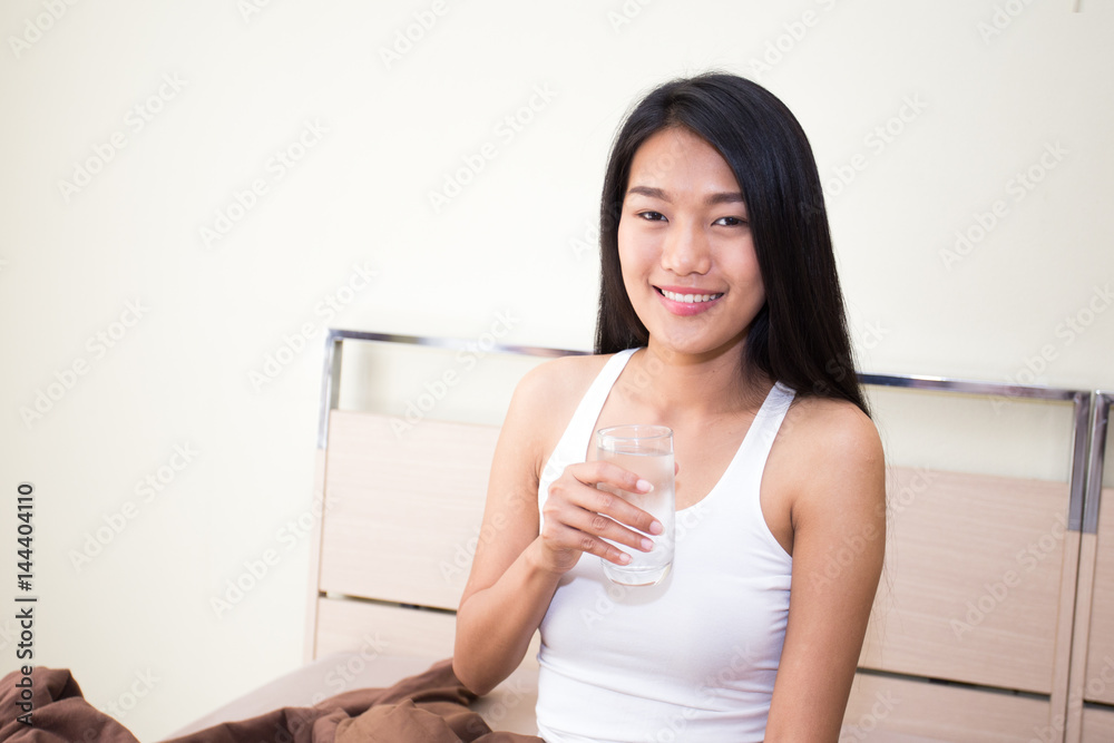 Beautiful asian woman with attractive smile while drinking water, Young woman portrait in bedroom. Beautiful asian woman with attractive smile while drinking water, Young woman portrait in bedroom.