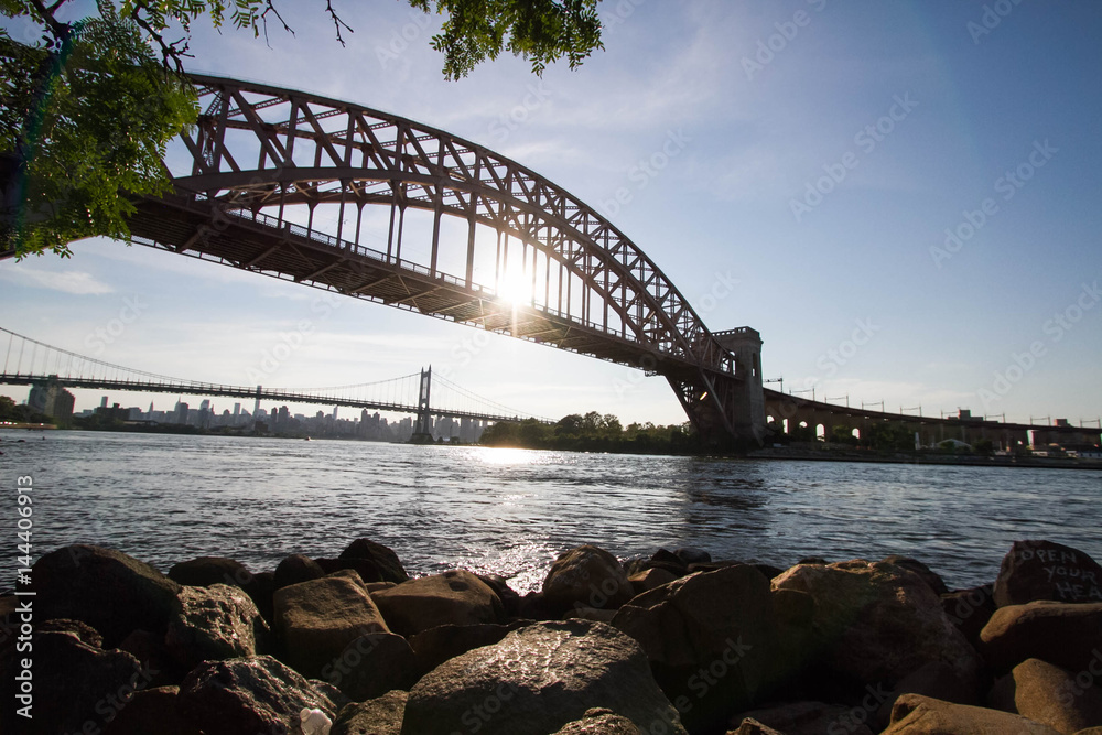 Obraz premium The Hell Gate Bridge, rocks and the sun reflect on the river, New York