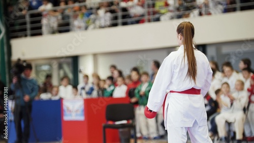 Sports kids - teenager girl sportsmen on karate at tatami arena - ready for fight