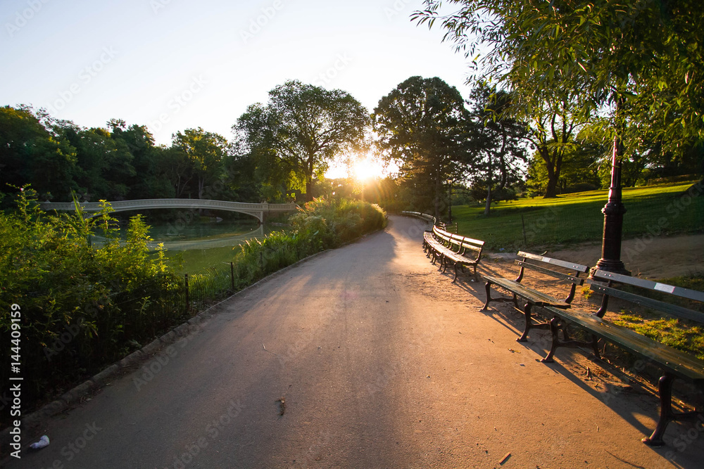 Walkway and park bench next to Bow bridge at Central Park with sunrise
