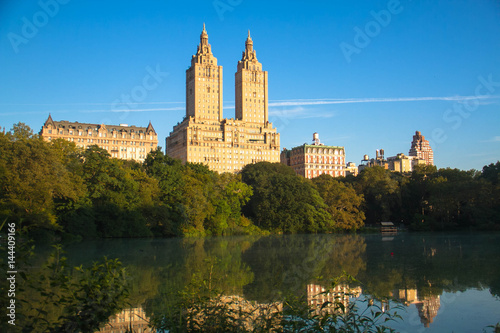 Buildings in Manhattan reflects on the lake at Central Park with blue sky, New York © Spinel