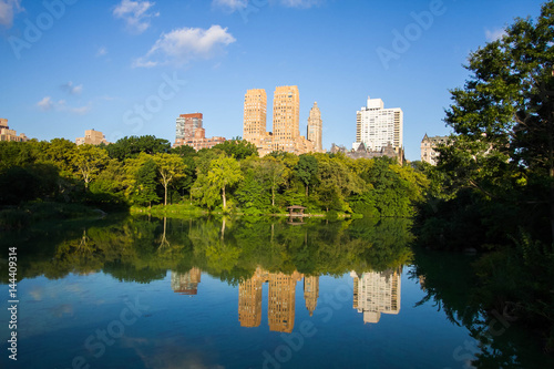 Fototapeta Naklejka Na Ścianę i Meble -  Buildings in Manhattan and trees reflect on the lake at Central Park