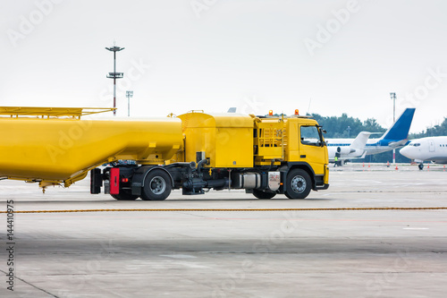 Yellow tank truck aircraft refueler at the airport apron