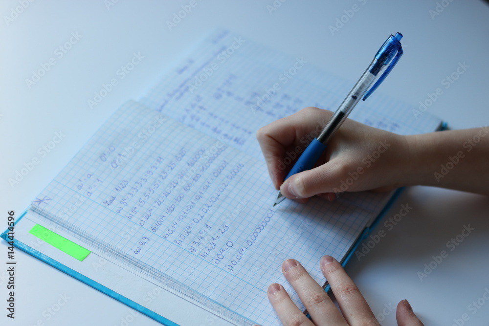 Pupil's hand writes maths task in notebook Pupil's hand writes maths task in notebook