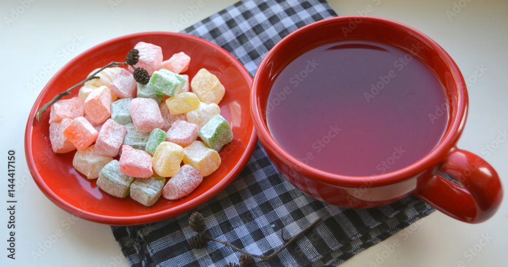 colorful Turkish Delight /Rahat Locum/ locum on a red plate with a cup of tea colorful Turkish Delight /Rahat Locum/ locum on a red plate with a cup of tea