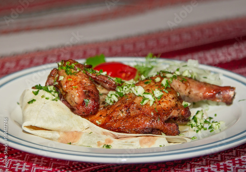 Grilled quail served on flatbread with cut onion and parsley on a plate