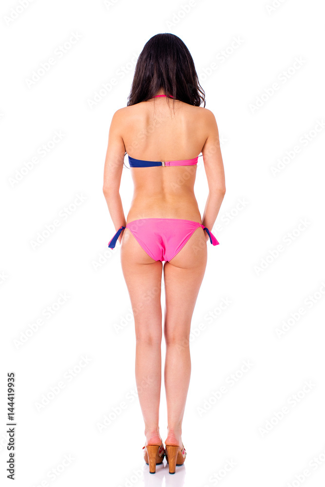 Fototapeta premium Back view. Snap model. Full length portrait of young woman wearing pink and blue bikini