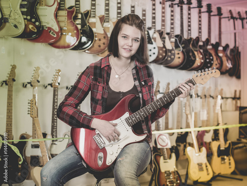 Teenage girl choosing electric guitar