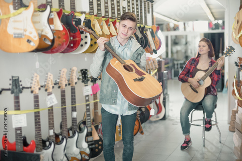 Teenagers examining guitars in shop