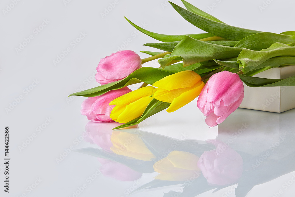Obraz premium Spring flowers. Pink and yellow tulips bouquet on a glass table. White background.