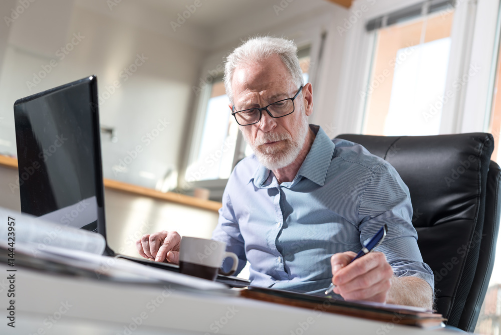Senior businessman taking notes, hard light Senior businessman taking notes, hard light
