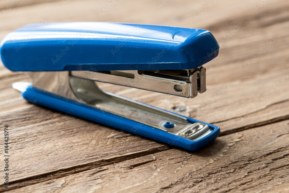 blue stepler on wooden background blue stepler on wooden background