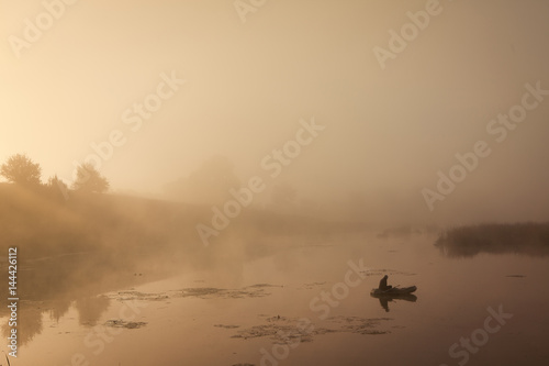 A misty morning by the lake. Small fishing boat at the lake. Space for text.