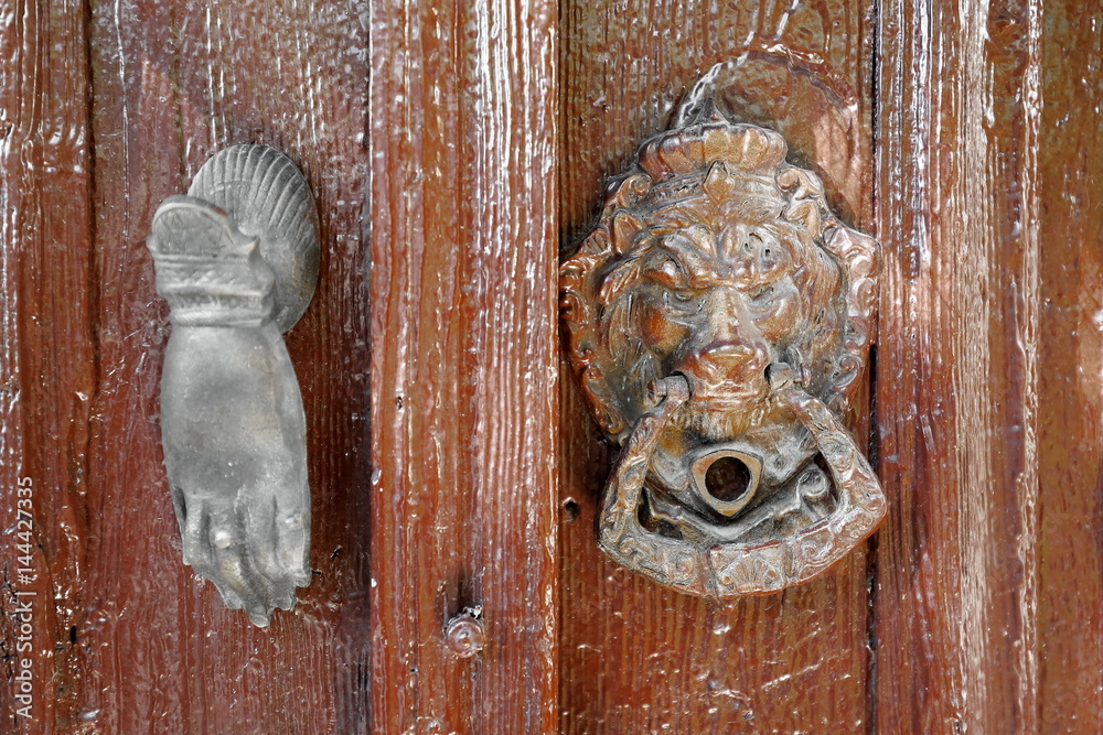 Lionhead-human hand shaped doorknockers hanging on old door. Kas-Turkey. 1786