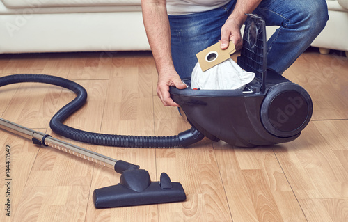 Man taking out a full dust bag from a vacuum cleaner   
