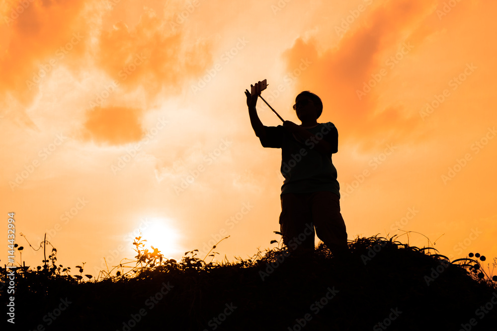 silhouette of smart woman take a selfie at hill on beautiful summer sunset
