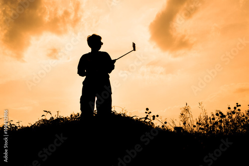 silhouette of smart woman take a selfie at hill on beautiful summer sunset