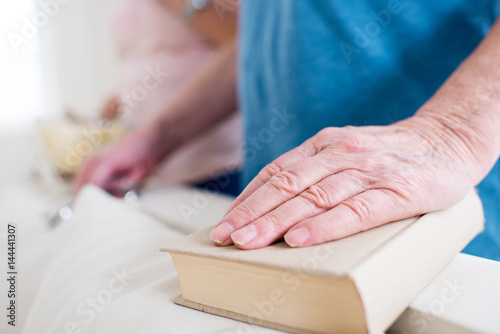 partial view of man's hand lying on book at home