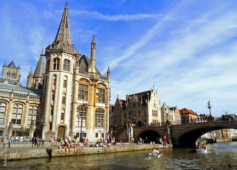 People chilling out at riverside In the afternoon of Sunday 18th May 2014, Ghent Historic Centre with Former Post Office and St Michael's Bridge, Belgium People chilling out at riverside In the afternoon of Sunday 18th May 2014, Ghent Historic Centre with Former Post Office and St Michael's Bridge, Belgium