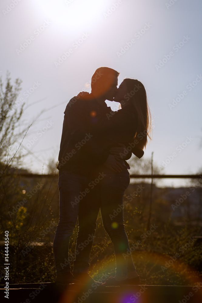 Man and woman kissing on the backdrop of the setting sun. Silhouette.