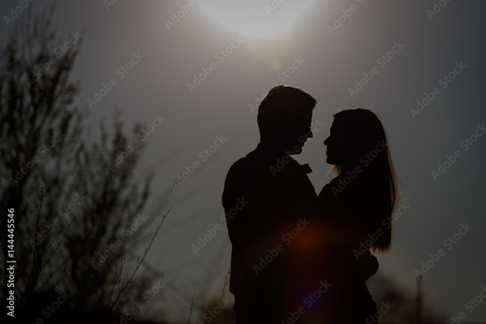 Man and woman hugging in the background of the setting sun. Silhouette.