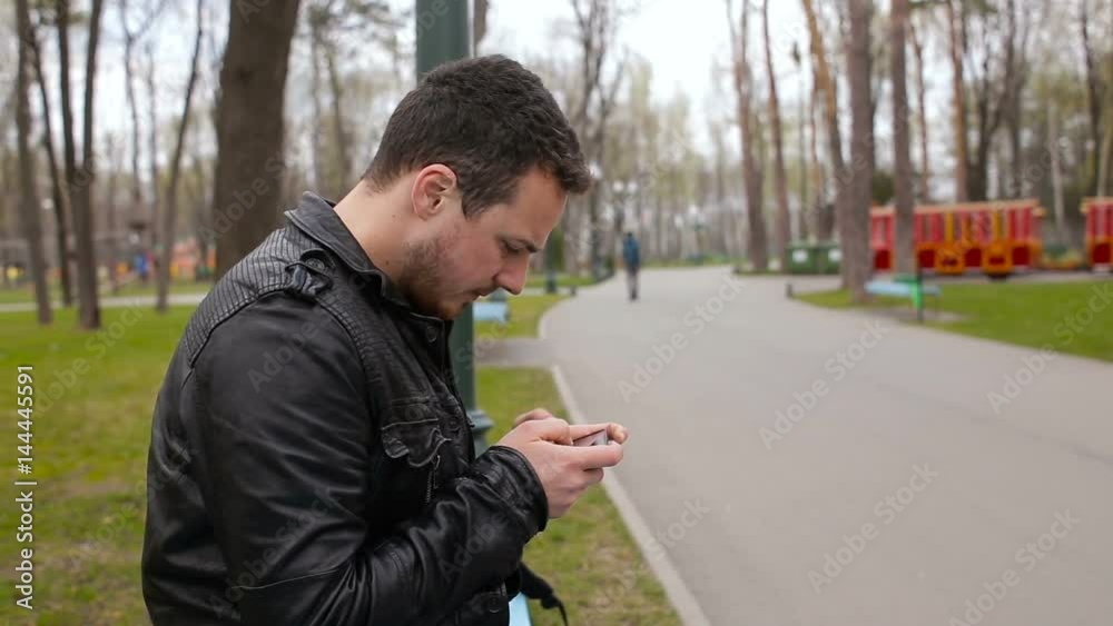 Young man playing on phone in the big park Young man playing on phone in the big park