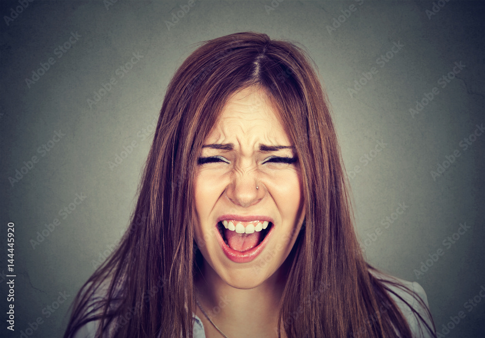 Headshot of an annoyed angry woman screaming.