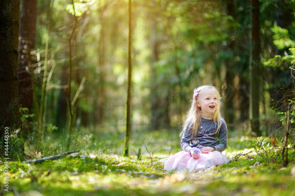 Adorable little girl picking the first flowers of spring in the woods on beautiful sunny spring day Adorable little girl picking the first flowers of spring in the woods on beautiful sunny spring day