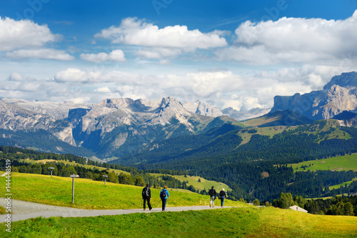 Tourists hiking in Seiser Alm, the largest high altitude Alpine meadow in Europe, stunning rocky mountains on the background.