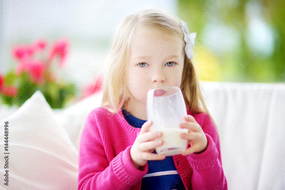 Cute little girl drinking fresh organic milk at sunny summer day. Healthy nutrition for children. Cute little girl drinking fresh organic milk at sunny summer day. Healthy nutrition for children.
