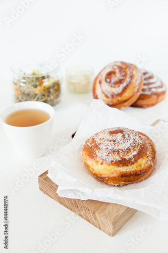 Herbal tea and sweet buns with sugar and cinnamon on a white background.