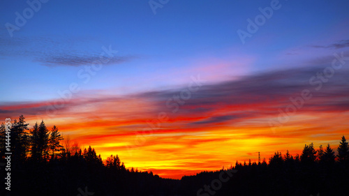 Blazing sunset over the evening hills forest. Flaming sky - the landscape in the setting sun. © maestrovideo