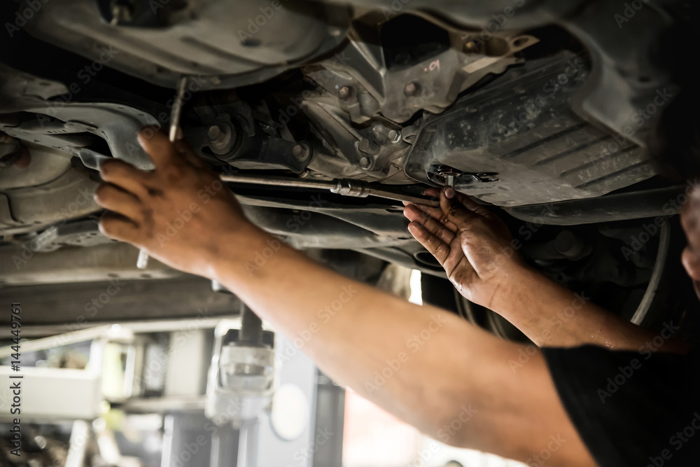 Φωτογραφία Close up of mechanic man hands at below of a car examining for change engine oil at the garage