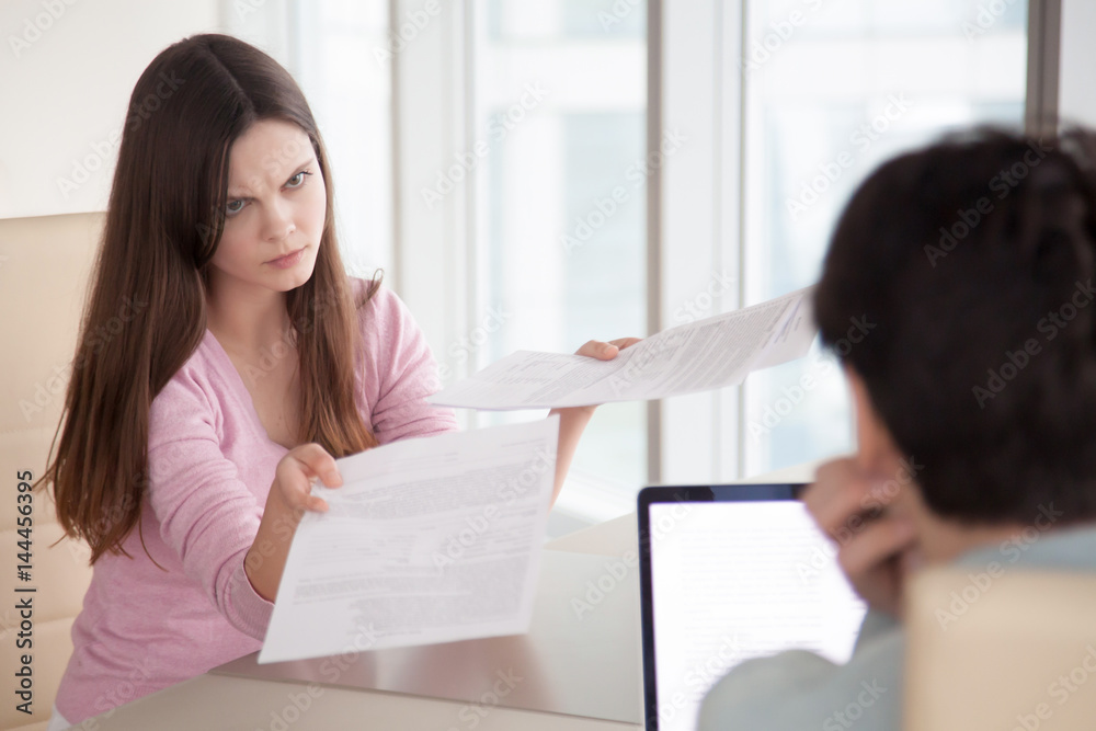 Angry businesswoman showing partner financial reports, documents, contracts, lady boss dissatisfied with work results, female manager mad at coworker due to paperwork error. Couple arguing over bills Angry businesswoman showing partner financial reports, documents, contracts, lady boss dissatisfied with work results, female manager mad at coworker due to paperwork error. Couple arguing over bills