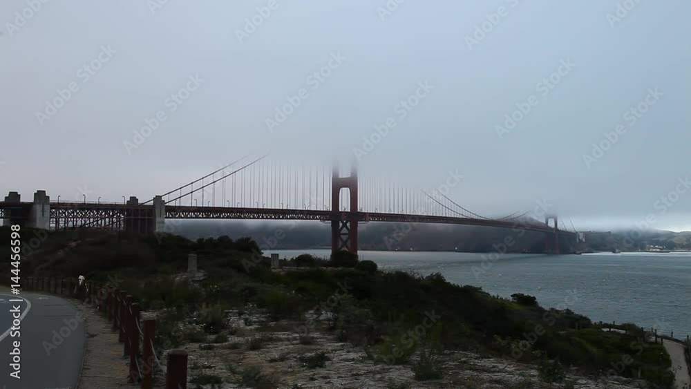 Foggy Golden Gate Bridge with grass as foreground from south shore. Symbol, icon and landmark of San Francisco, California, United States. Fog in summer. American travel concept. Foggy Golden Gate Bridge with grass as foreground from south shore. Symbol, icon and landmark of San Francisco, California, United States. Fog in summer. American travel concept.