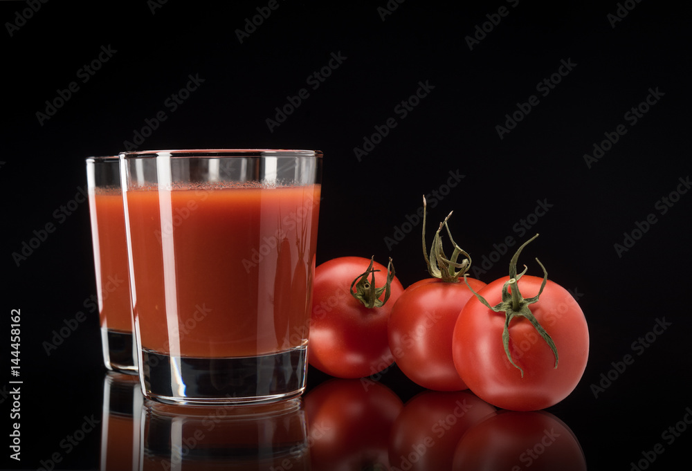 Still life with tomato juice in glass on black background