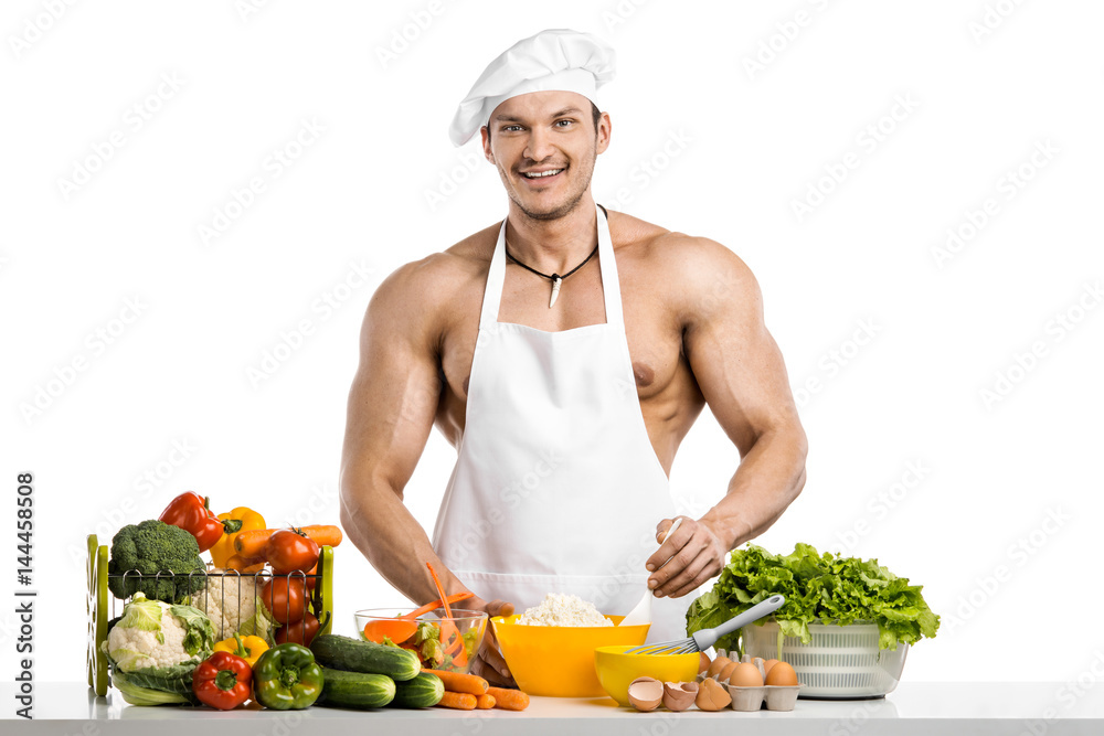 Man bodybuilder in white toque blanche and cook protective apron cooking cottage cheese and vegetables