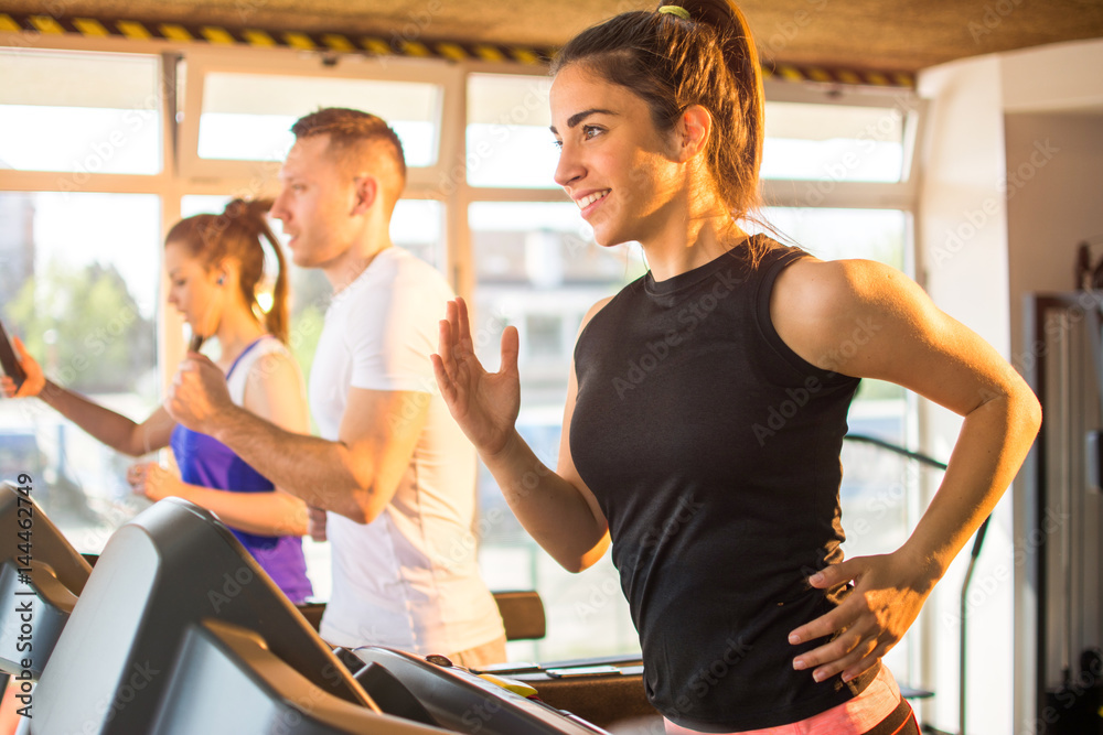 Smiling sporty woman running on a treadmill in gym. Smiling sporty woman running on a treadmill in gym.